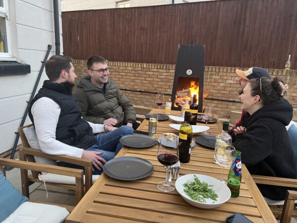 Friends laughing around fire pit in luxury metal chiminea